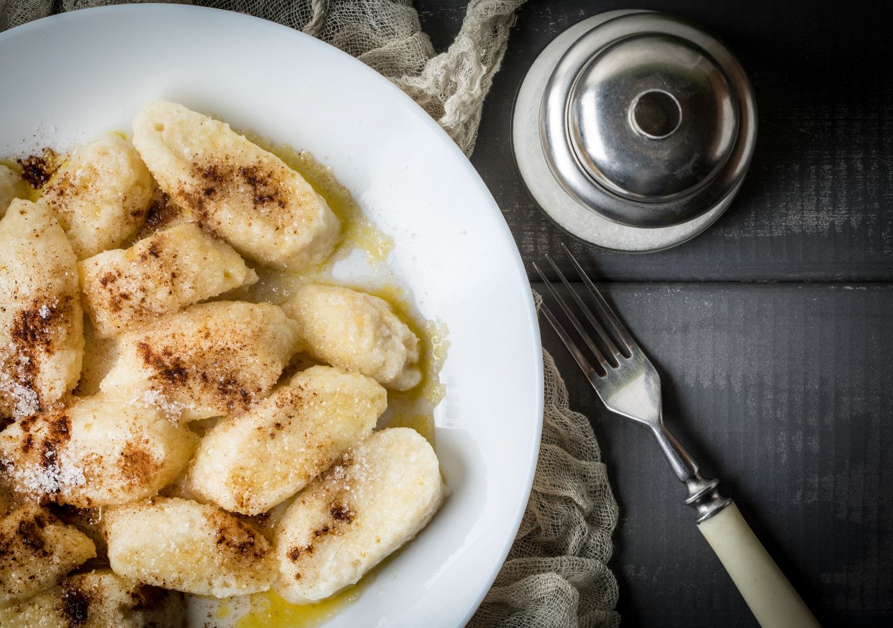 Ugotowane kluski leniwe podane z cynamonem, masełkiem i cukrem