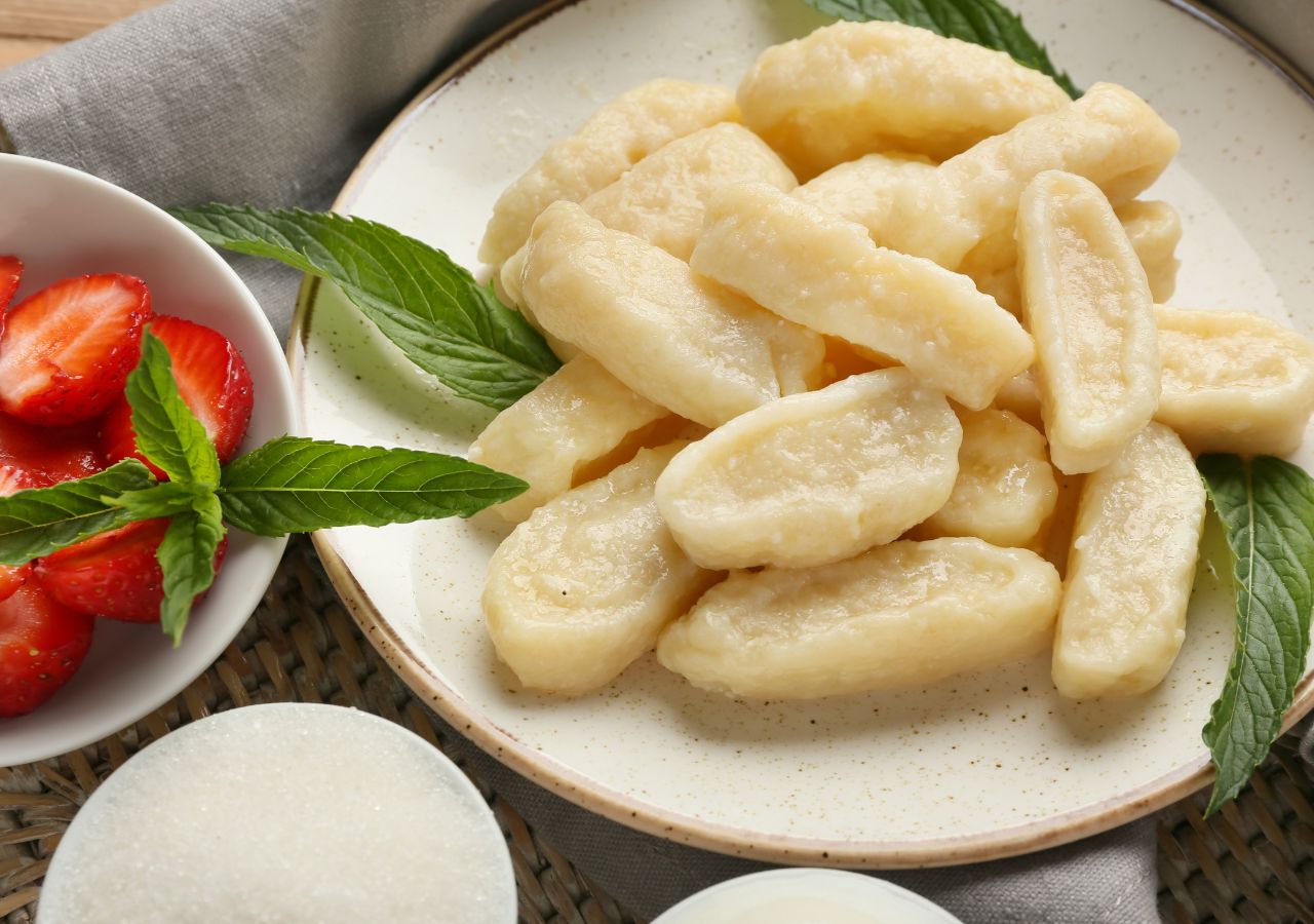 Ugotowane pierogi leniwe, podane na słodko z dodatkiem świeżych owoców