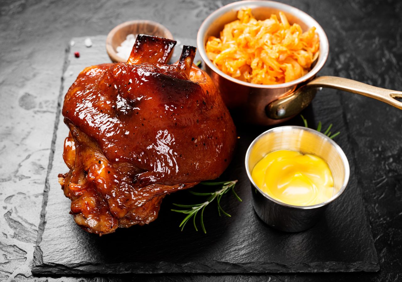 Pieczona golonka wieprzowa w glazurze, podana z sałatką i musztardą