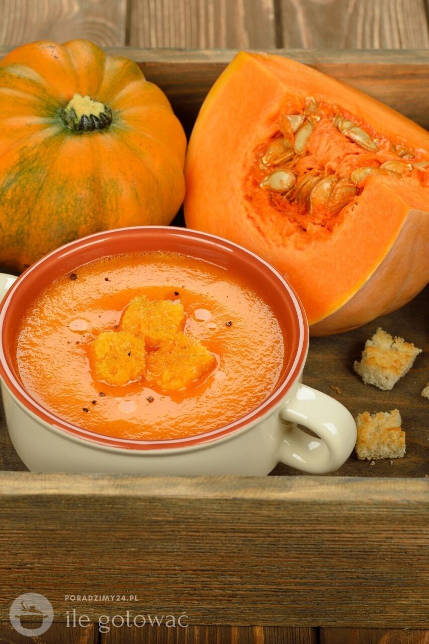 Zupa krem z dyni hokkaido podana w barszczówce, obok przekrojona dynia