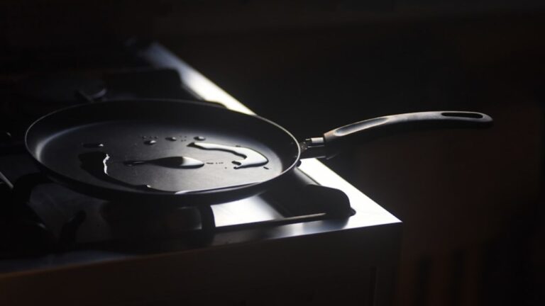 Czarna patelnia z olejem na czarnej płycie z palnikami