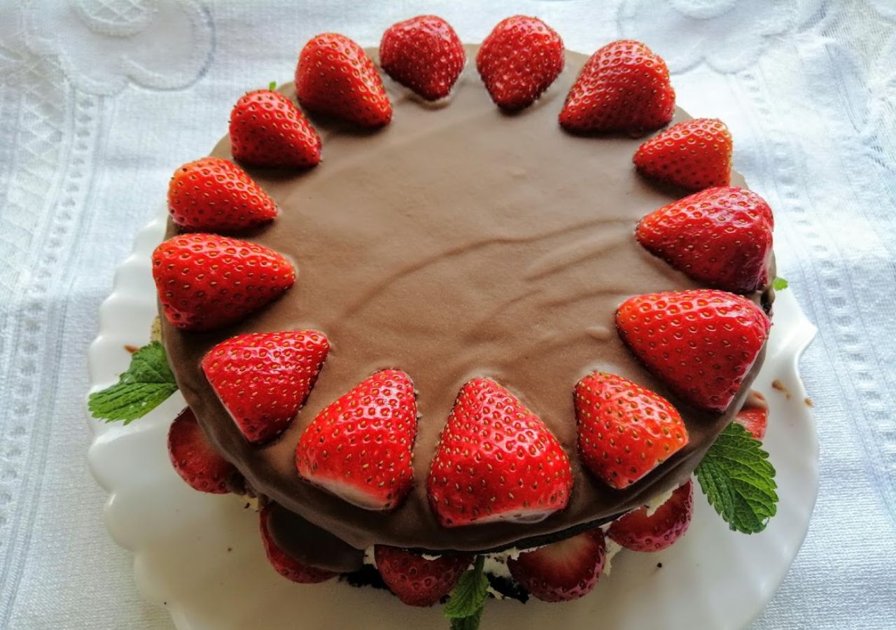 Tort czekoladowy z truskawkami polany polewą z mlecznej czekolady