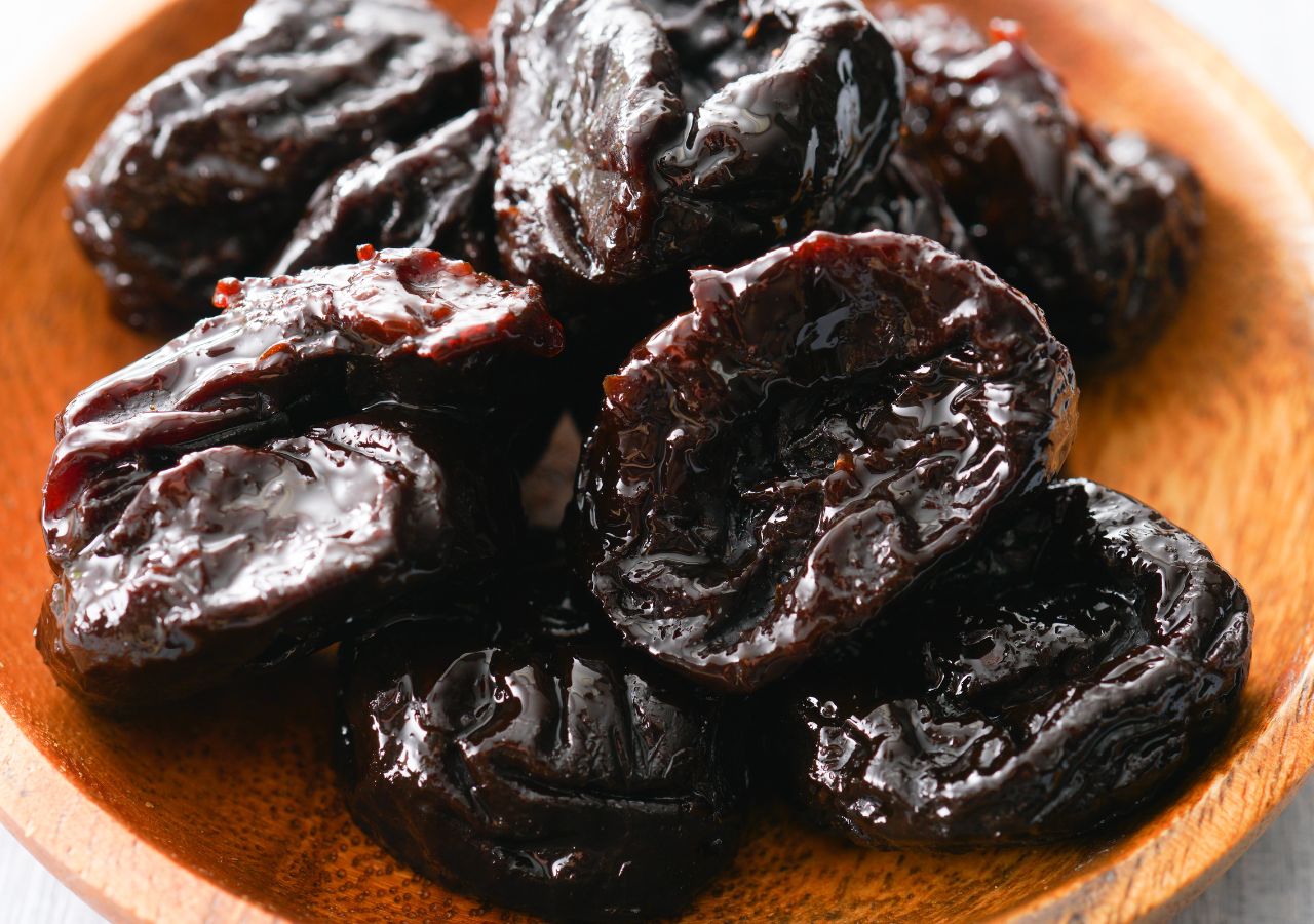 Suszone śliwki w drewnianej miseczce